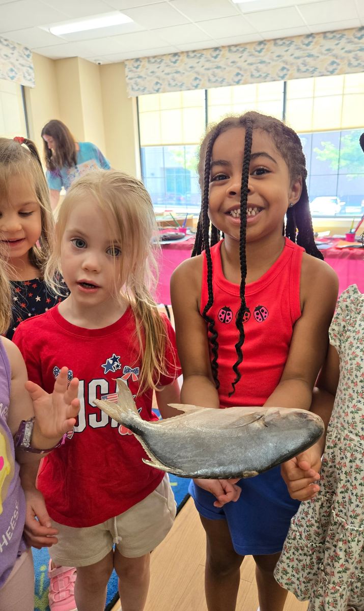Two girls holding up a model fish