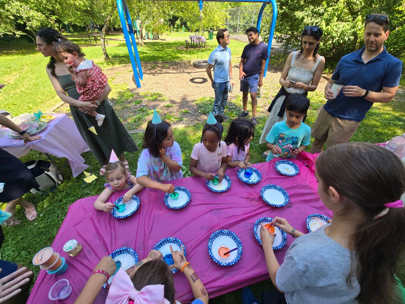 Kids around an outdoor table of colorful science bowls