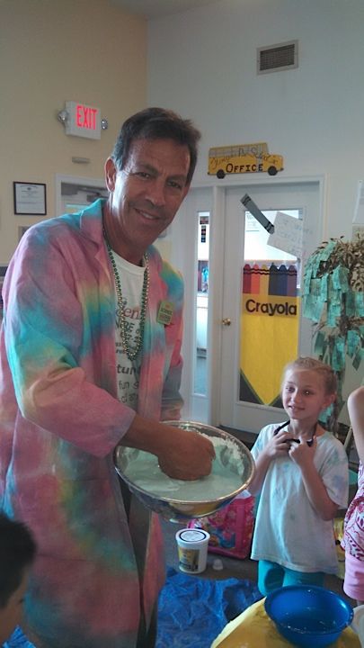 Nature Jack in a tie-dye lab coat holding a tray of foam while a preschooler watches