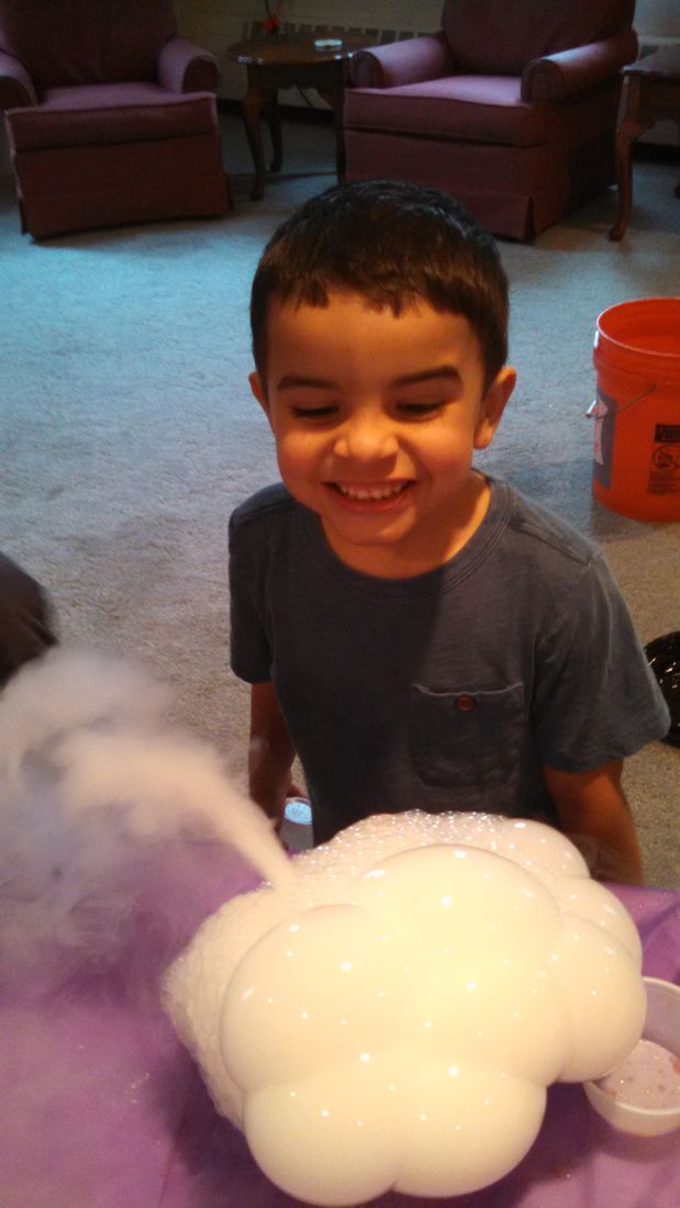 A smiling boy watching a fog-filled bubble from dry ice