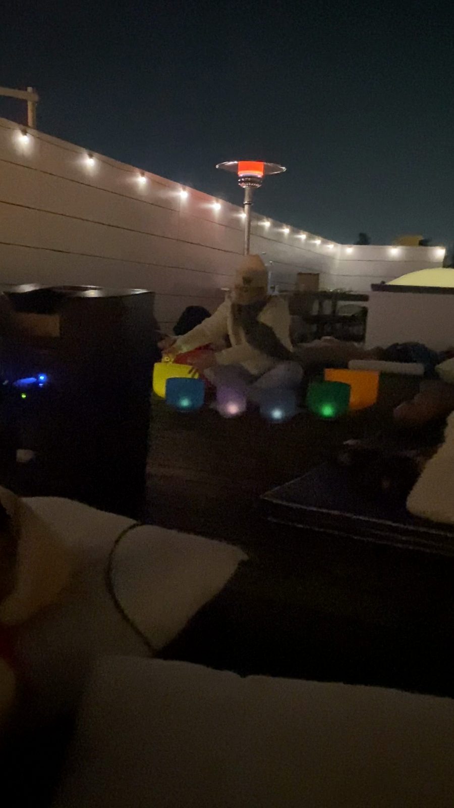 Glowing crystal singing bowls under string lights on a rooftop at night